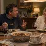 A family talks together around a dining table set with roasted potatoes, gravy, and glasses of red wine.